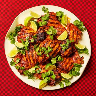 Salsa Grilled Chicken Thighs on a plater garnished with fresh cilantro and lime wedges.